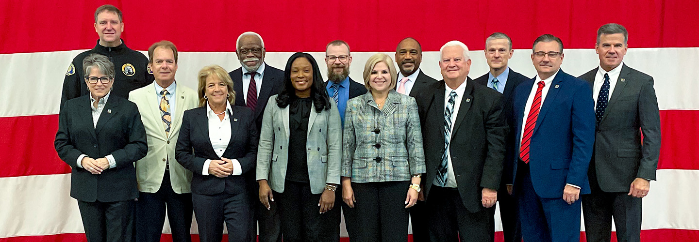 The FirstNet Authority Board meeting in August 2023 FirstNet Authority Board members stand in front of an American flag before the August 2023 meeting