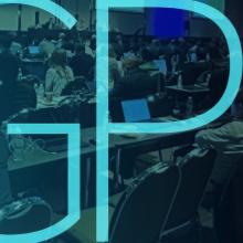 A large group of people dressed in business attire seated at conference tables while taking notes on electronic devices at a 3GPP plenary session in September 2024; "3GPP"   