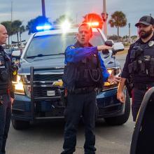 Six police officers talking in front of three police vehicles at an intersection in St. Augustine, Florida  