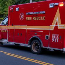 Ambulance and other vehicles from the Jackman Moose River Fire Rescue agency responding to a vehicle accident in a ditch beside a rural road. 